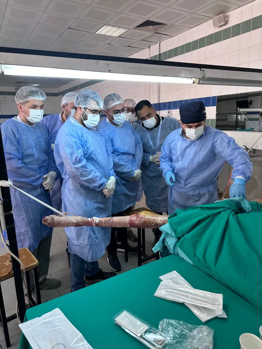 Surgeon guiding a group of participants through a step at the cadaveric station